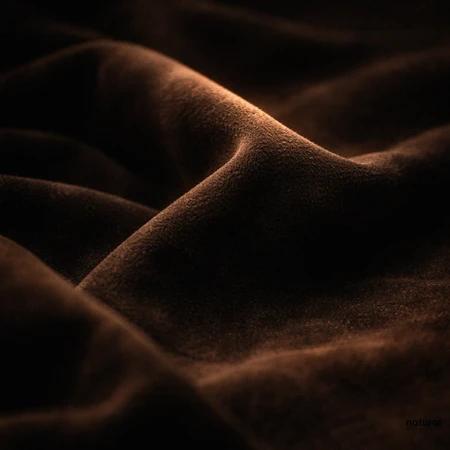Extreme close-up of luxurious dark chocolate-brown suede fabric with soft flowing folds, rich velvety textures and subtle warm highlights against a deep shadowy background, representing the earthy, floral, woody, soft leather and animalic aroma of Fleur de Cuir Process E, a specialty perfumery ingredient.