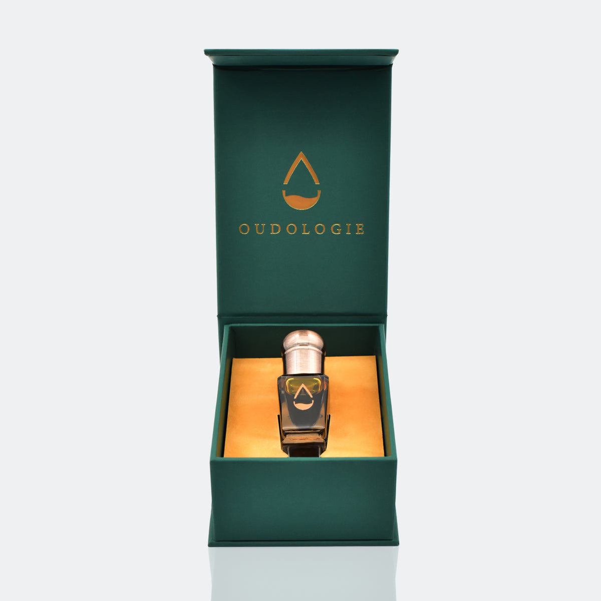 Oudologie luxury oud oil bottle presented inside an open dark green gift box with gold interior.
