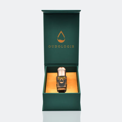 Oudologie luxury oud oil bottle presented inside an open dark green gift box with gold interior.